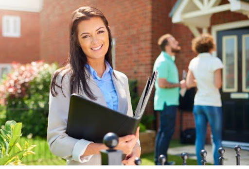 female real estate agent smiling near couple