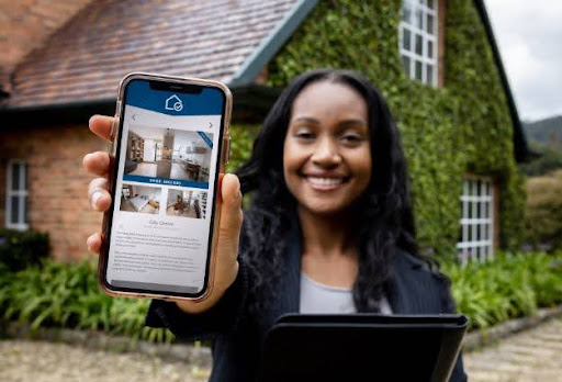 young woman holding phone in front of house