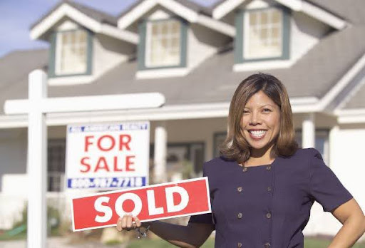 female real eastate agent holding sold sign