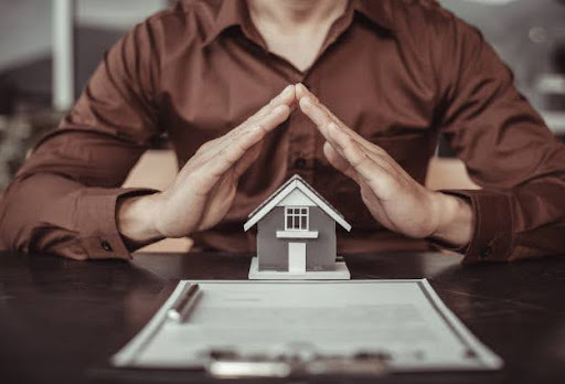 person with hands over little house