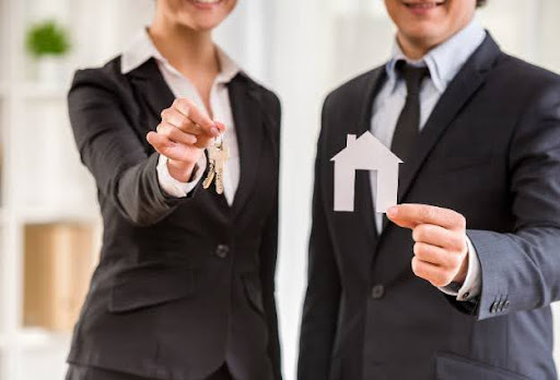 two real estate agents holding keys and house