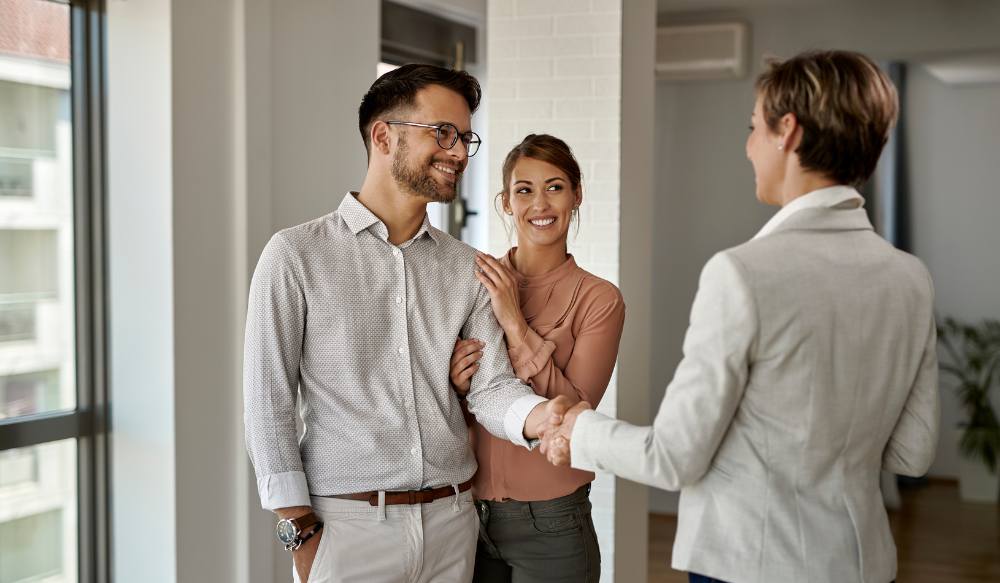 couple shaking real estate agent hand
